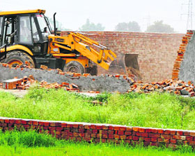  A JCB machine demolishes an illegal structure in the Kundli industrial area on Thursday. 