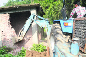 A JCB machine demolishes an illegal structure in Mandi on Friday. 