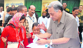 Chief Minister Vijay Bahuguna presents cheques to families of the natural disaster victims at Lambgori village near Guptkashi on Saturday.