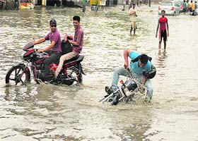 A biker loses control on a water-logged road during heavy rain in Jalandhar