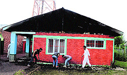 A group of men collect wooden logs which were burnt after the Panchayat Ghar was set ablaze on Friday night, in Sopore on Saturday