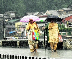 Women walk along Dal Lake in the rain in Srinagar on Saturday