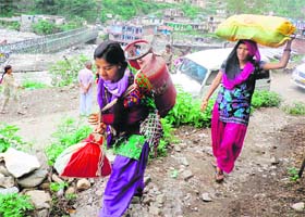 A woman and her daughter carry relief material and a gas cylinder near Sonprayag, Rudraprayag