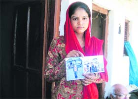 Uma with the photographs of her brothers Umesh and Pradeep, who were killed in the June 16 disaster