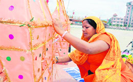 A woman gives final touches to a decorated Kanwar. 