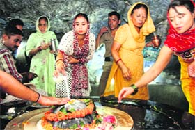 Women perform jalabhishek at the Tapkeshwar Mahadev Temple in Dehradun on Monday