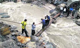 Chief Minister Vijay Bahuguna crosses a makeshift bridge over a stream during his visit to Kedarnath valley on Monday