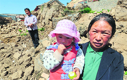Local residents stand in front of their house destroyed by an earthquake at Dingxi on Tuesday.  AFP