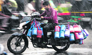Braving heavy rain, a delivery boy carries tiffin boxes for his customers on a motorcycle in Jalandhar on Wednesday. 