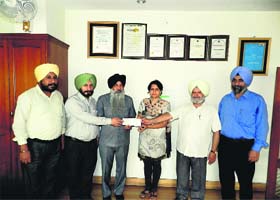 Avtar Singh Sampla, trustee, and Dr Lakhwinder Singh, principal, receive the grant