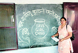 Santosh Dahiya standing in front of a board with a slogan of 'Save the Girl Child'