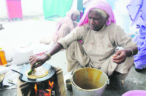 A woman cooks a dish in a traditional way, using a leaf, at the Bebe Di Rasoi during the festival. 
