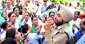 Protesting members of Government Rajindra Hospital Nursing Association (contract) argue with a police officer after blocking the car of Punjab Medical Education and Research Minister Bhagat Chunni Lal in Patiala on Friday. 