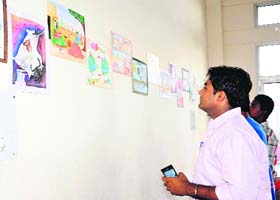 Visitors look at the paintings on display during the contest organised as part of the environment and natural farming festival in Bathinda on Sunday