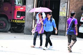 Sun and Shade: Girls use an umbrella to protect themselves from the harsh sun on Sunday afternoon in Bathinda