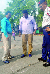 A traffic police official and others at the spot where a motorcyclist was killed in the police firing on Janpath Road near the Le Meridien Hotel in New Delhi on Sunday