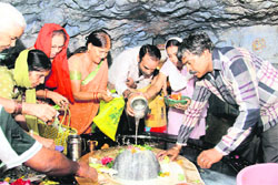 Devotees offer Ganga jal at the Tapkeshwar temple in Dehradun on Monday on the first Monday of Sharavan month.