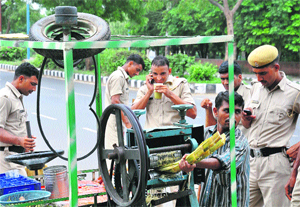  Police officials quench their thirst by drinking cane juice at the Leisure Valley park in Gurgaon.