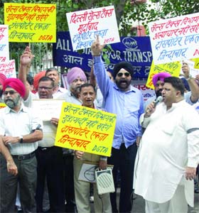 Members of the Delhi Goods Transport Association shout slogans during a protest against the Sale Tax Department at ITO in New Delhi on Tuesday