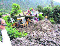 A JCB machine removes muck and boulders that had entered a house at Deol village.