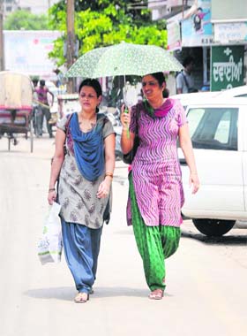 Matching steps: Women walk under the shade of an umbrella on a hot summer afternoon in Bathinda on Wednesday