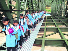 Students of Temeriya village in the Kedar valley cross an under-construction bridge to go to school.