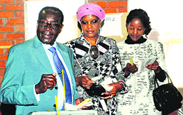 Zimbabwe's President Robert Mugabe (L) casts his vote along with his wife Grace and daughter Bona (R) at a polling booth in Harare