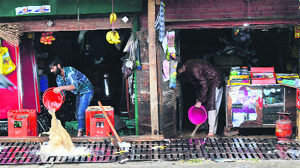 Shopkeepers clear water from their shops in Pantha Chowk area on the Srinagar-Jammu National Highway in the wake of waterlogging in the area following heavy rainfall on Thursday morning.