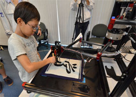 A boy writes a Chinese letter for study with a calligraphy robot, which mimics the exact brush strokes of a master calligrapher, at a science workshop for elemenatry children at Keio University in Yokohama, suburban Tokyo. The motion copy robot, developed by Japans Keio University Associate Professor Seiichiro Katsura, can recreate master works and the users can experience the same pressure and the same gestures of brush works by master painters or calligraphers. 