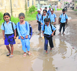 Students of Government School, Bharonjia village, tread on a waterlogged road.