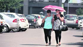 Under cover: With scorching heat prevalling, girls take cover under an umbrella in Jalandhar on Saturday