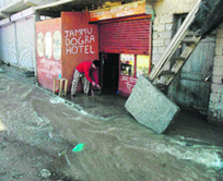 A shopkeeper removes rainwater from his shop in Kargil.