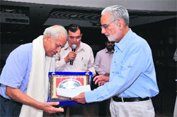 Chaman Lal Malhotra receives an award from IS Bindra, president, PCA, during a function at the Dhruv Pandove Conference Hall, PCA Stadium, in Mohali on Sunday. 