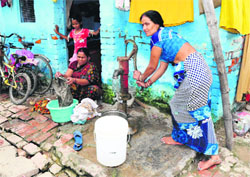 Women use water for drinking, washing and cleaning purposes from a hand pump installed outside a house in Colony Number 5 in Chandigarh. 