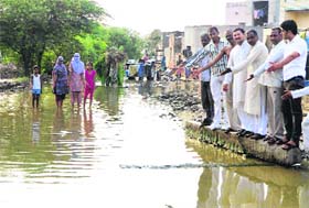 Residents show a flooded street at Kasrenti village in Rohtak district on Sunday