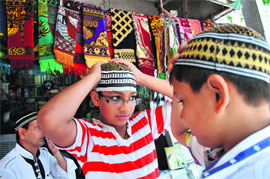 Boys buy skull caps ahead of Eid-ul-Fitr at the Talab Khatinkan market in Jammu on Sunday. 