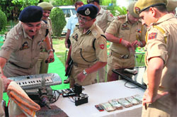 Police officers with the cash and valuables recovered from them in Jammu on Sunday.