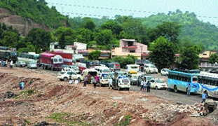 Vehicles stranded as Kashmiri Pandits block the Jammu-Sringar national highway in protest against the killing of a man at Nagrota on Tuesday.