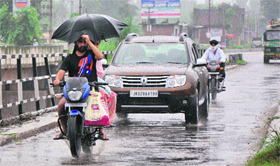 Commuters brave the rain in Jammu on Monday.