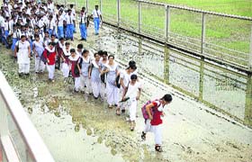 After the morning showers, participants crossing a muddy path after rehearsing for a cultural programme at Guru Gobind Singh Stadium in Jalandhar on Tuesday