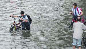 Students wade through knee-deep water on Domoria Bridge Road.