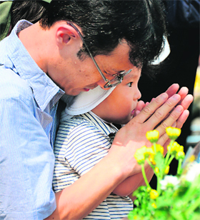 A father and his son pray for victims of the 1945 atomic bombing in front of the cenotaph at the Peace Memorial Park in Hiroshima on Tuesday.