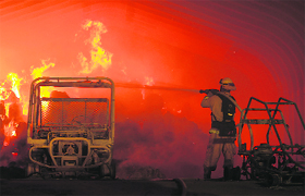 A firefighter hoses down destroyed ranch vehicles at the Falls Fire, west of Lake Elsinore in California, on Monday. The wildfire grew to at least 1,500 acres, prompting mandatory evacuations of the communities of Lakeland Village, Rancho Capistrano and Decker Canyon.