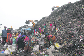 The Municipal Corporation deploys JCB machines for the compaction of garbage piles, which have spilled over on the approach road to the dump site at Wariana village in Jalandhar on Wednesday. 