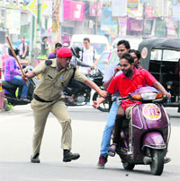 A policeman intercepts youths for triple riding on a scooter, and that, too, without wearing helmets in Dehradun on Friday.