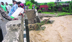 People gather on the spot where flash flood has damaged an approach road.