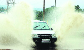  A car passes through a waterlogged road after a heavy rainfall in Jammu on Friday.