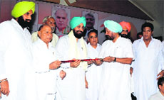 Senior Congress leader Amarjit Singh Samra honours PPCC chief Partap Singh Bajwa with a sword in Nakodar on Friday.