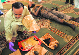 A police official displays explosives next to the body of a suicide bomber at a mosque near Islamabad on Friday.