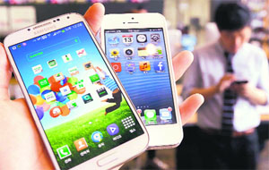 An employee of a smartphone showroom shows Samsung Galaxy S4 (L) and Apples iPhone5 in Seoul.